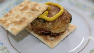 fried baltimore coddie between 2 saltine crackers with a dallop of yellow mustard